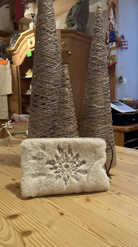 Pochette in pelliccia beige o bianca con fiocco di neve argentato, appoggiata su tavolo