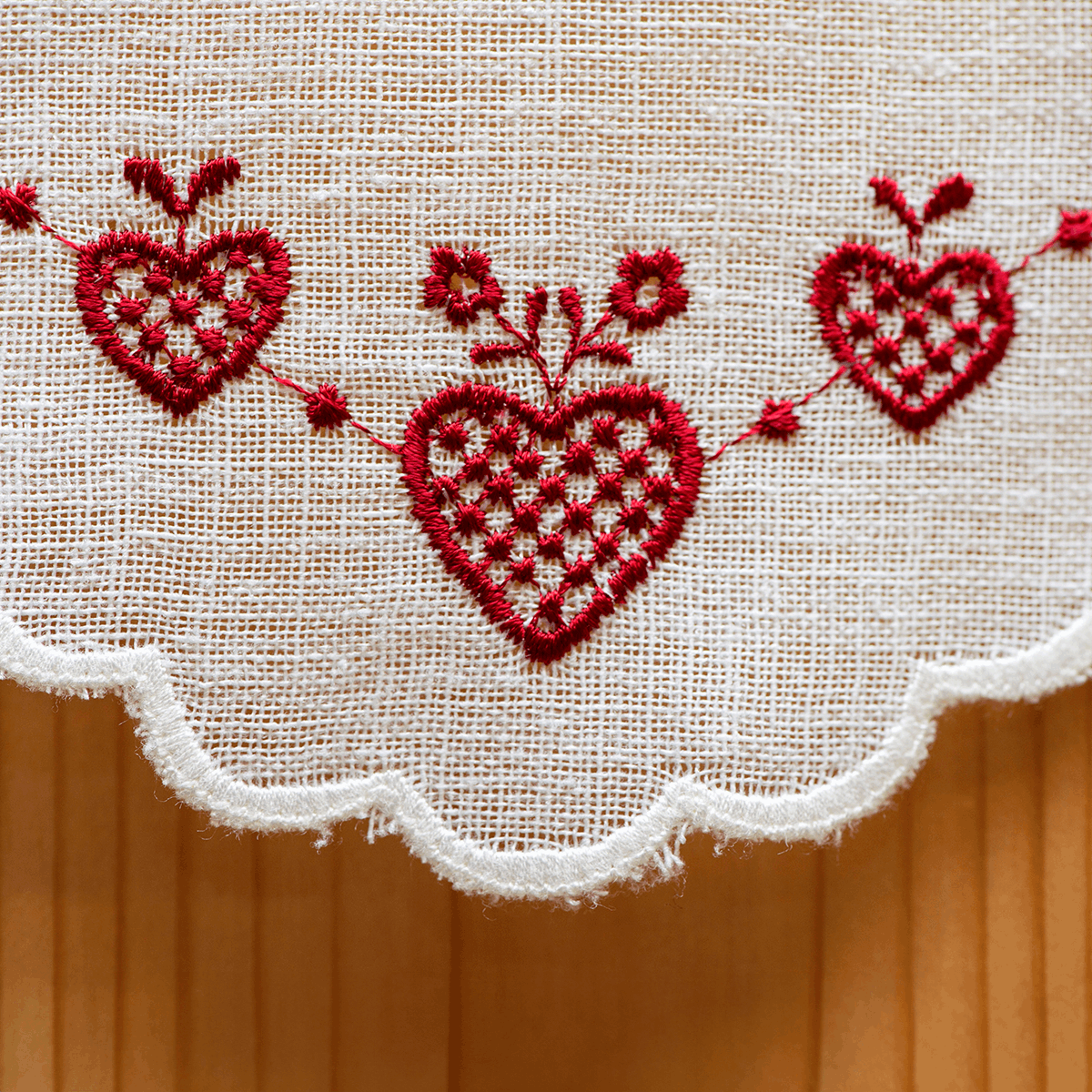 Dettaglio del fondo della tenda tirolese rossa con bretelle e cuori ricamati, moduli 16 cm